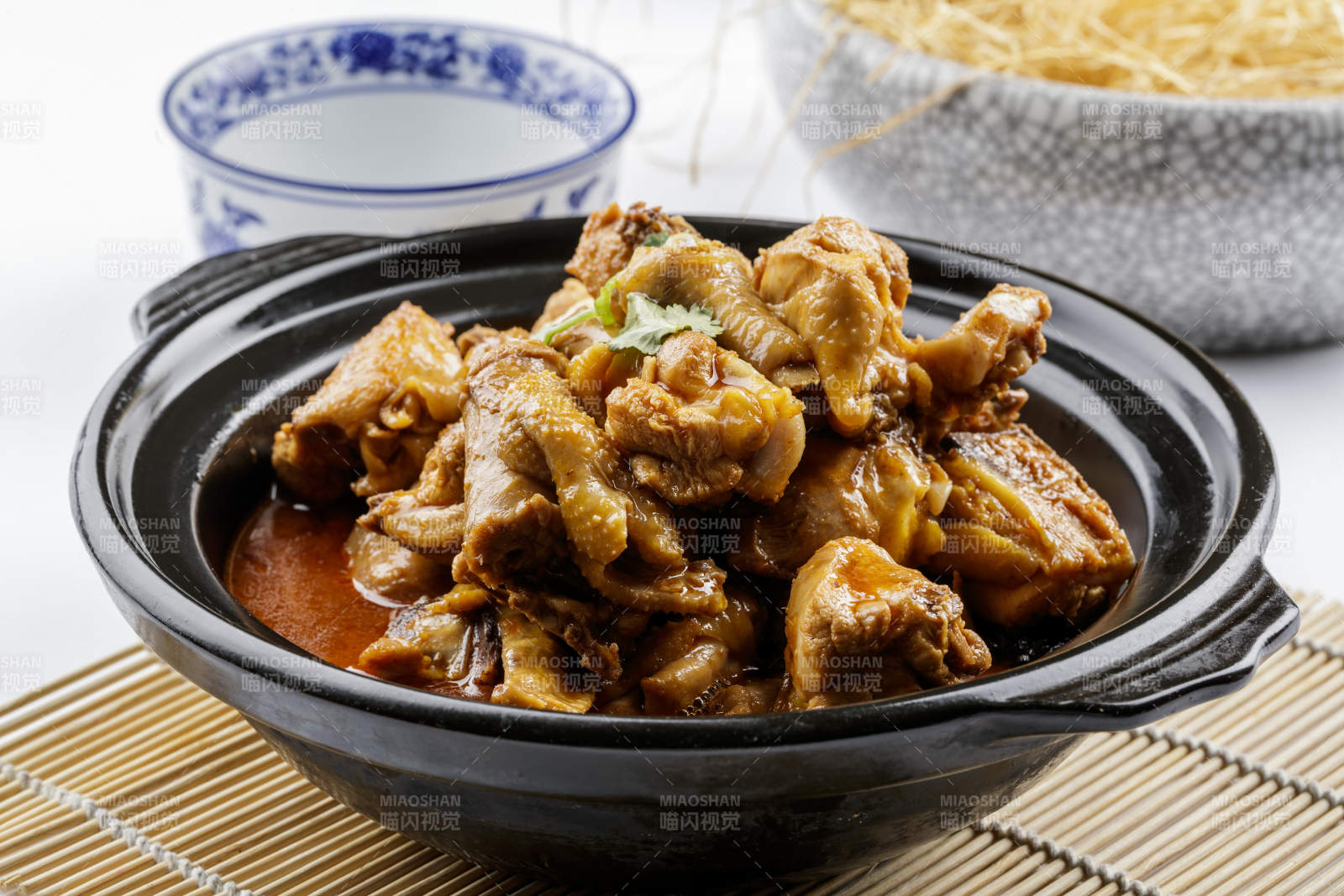 黑色砂锅装的文火散养鸡摆放在寿司帘上图片