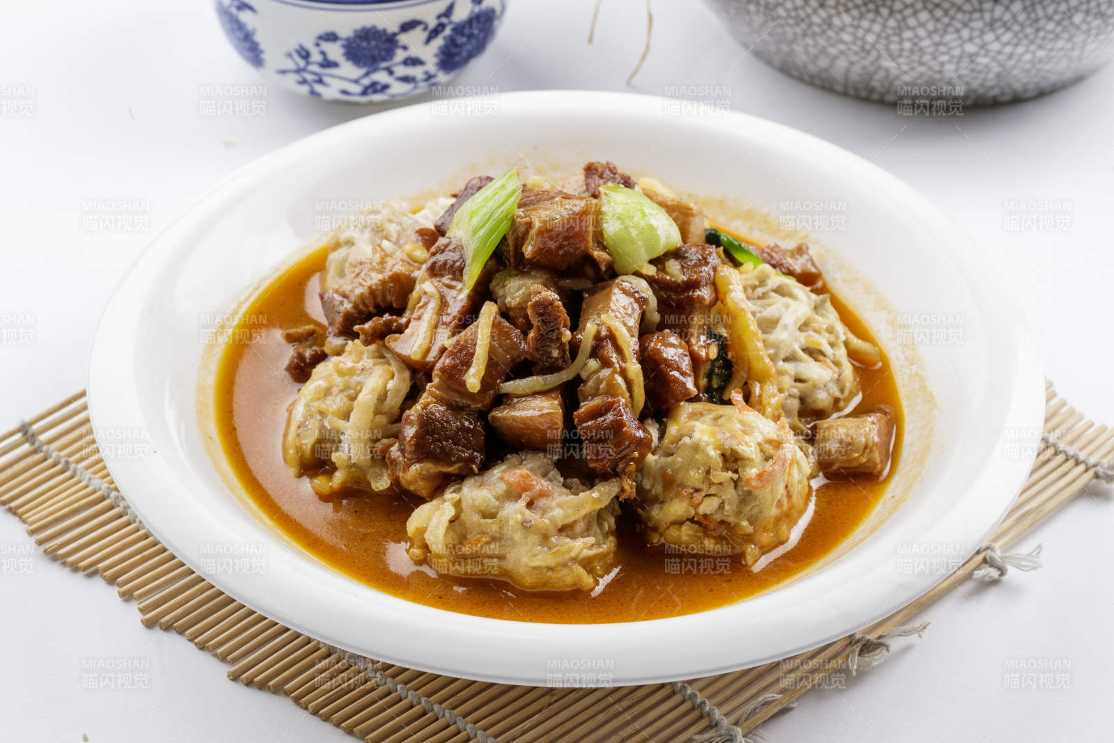 红烧肉炖土豆丸子摆放在寿司帘上图片