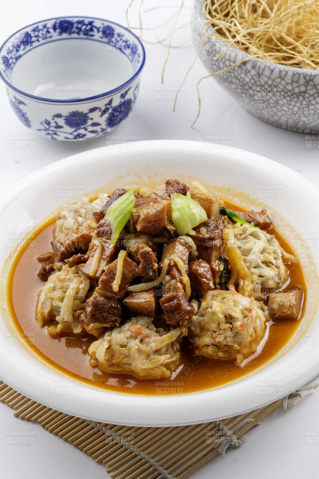 红烧肉炖土豆丸子摆放在寿司帘上图片