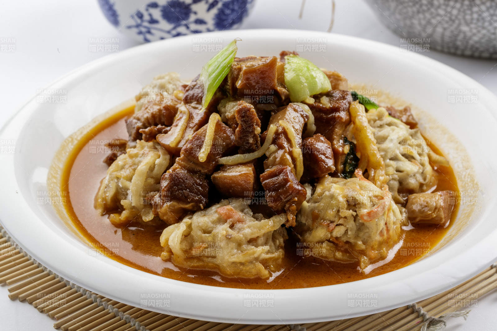 红烧肉炖土豆丸子摆放在寿司帘上图片