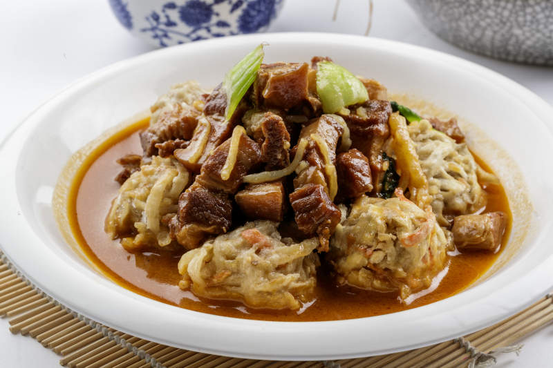 红烧肉炖土豆丸子摆放在寿司帘上图片