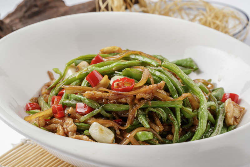 寿司帘上的元宝瓷盘装的黄花豇豆炒肉丝图片