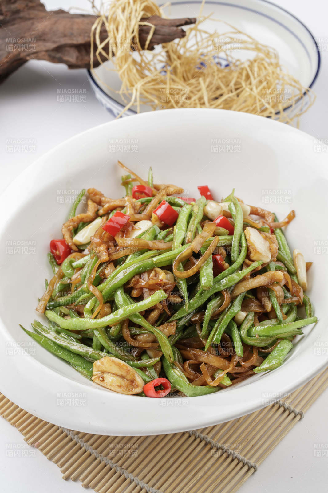 寿司帘上的元宝瓷盘装的黄花豇豆炒肉丝图片