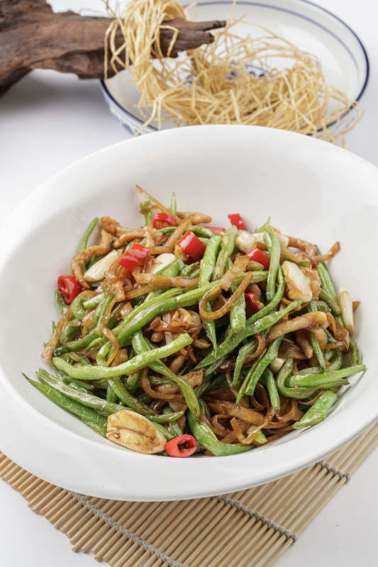 寿司帘上的元宝瓷盘装的黄花豇豆炒肉丝图片