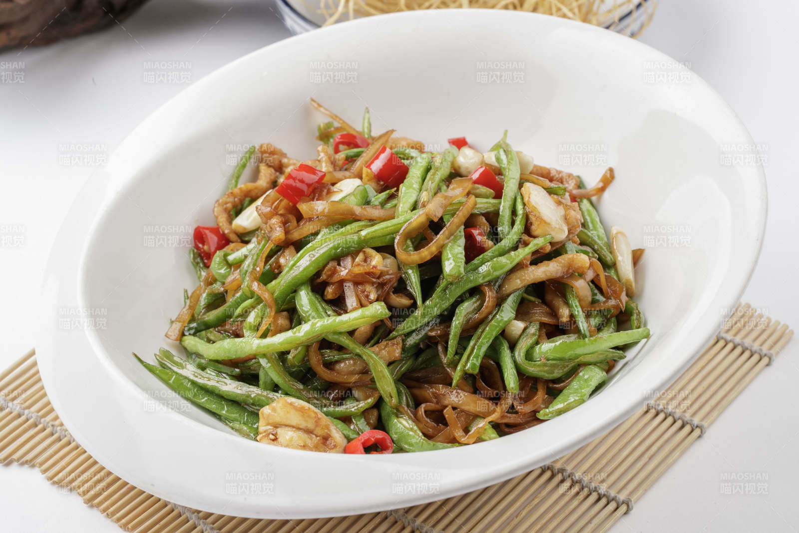 寿司帘上的元宝瓷盘装的黄花豇豆炒肉丝图片