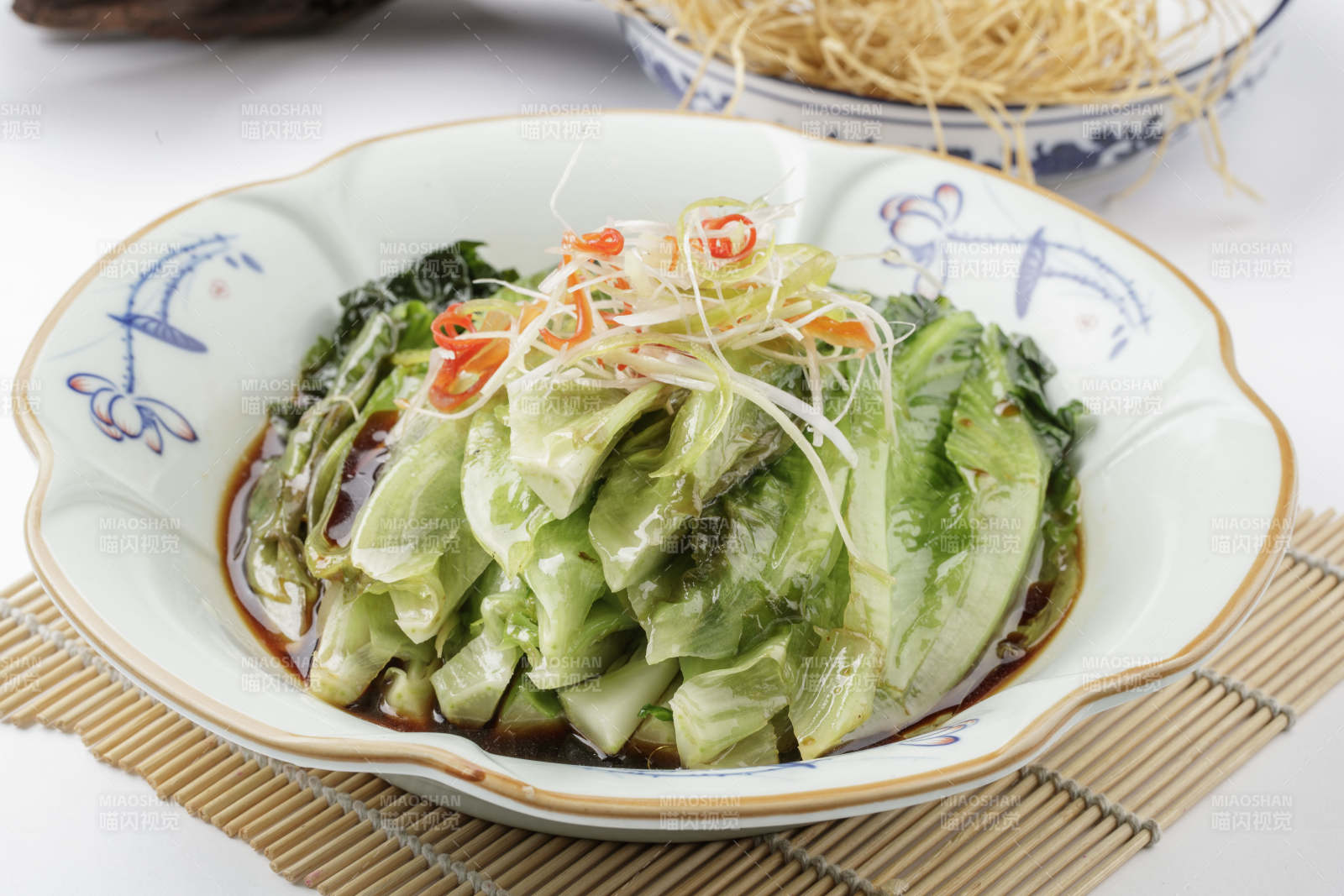 寿司帘上的复古瓷盘装的耗油菜心图片