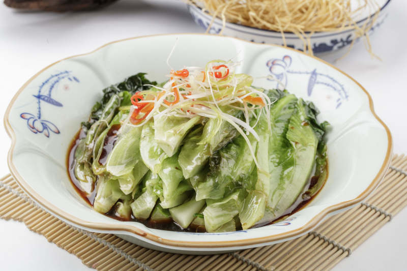 寿司帘上的复古瓷盘装的耗油菜心图片