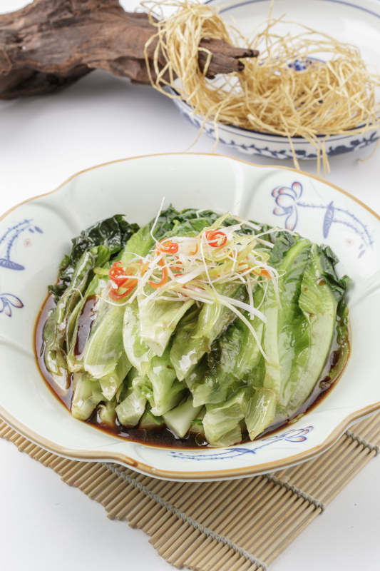 寿司帘上的复古瓷盘装的耗油菜心图片