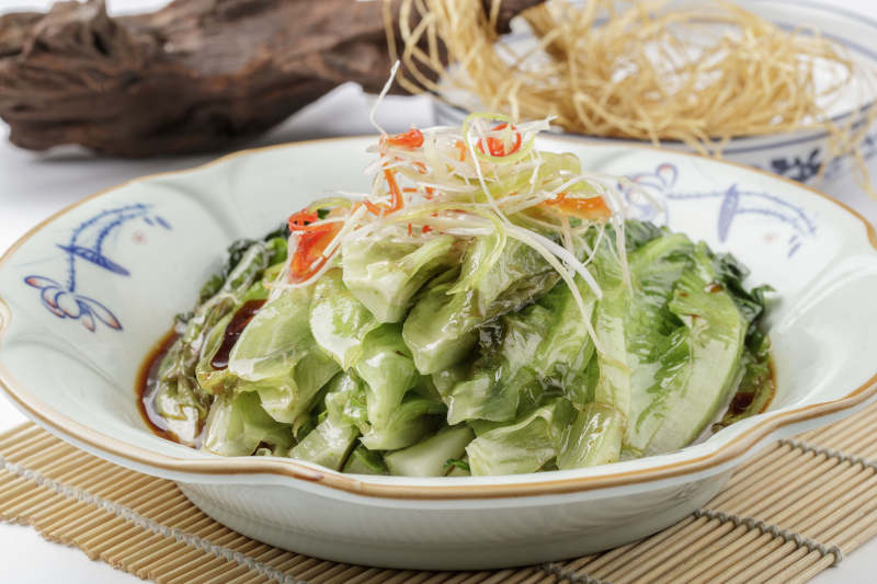 寿司帘上的复古瓷盘装的耗油菜心图片