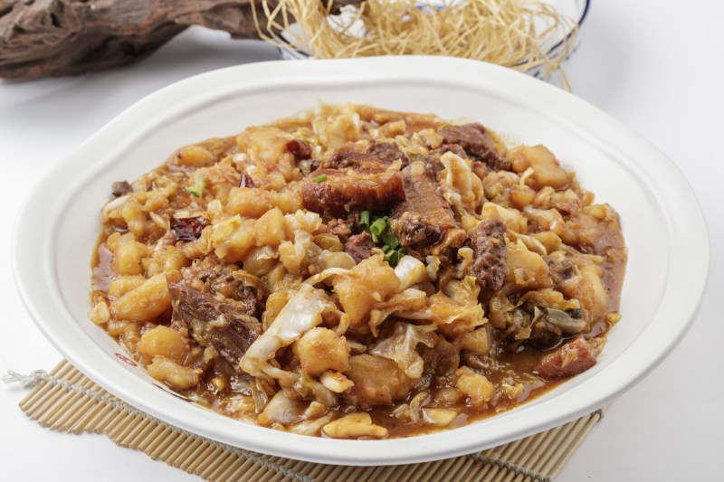 寿司帘上的环纹瓷盘装的一品乱炖图片