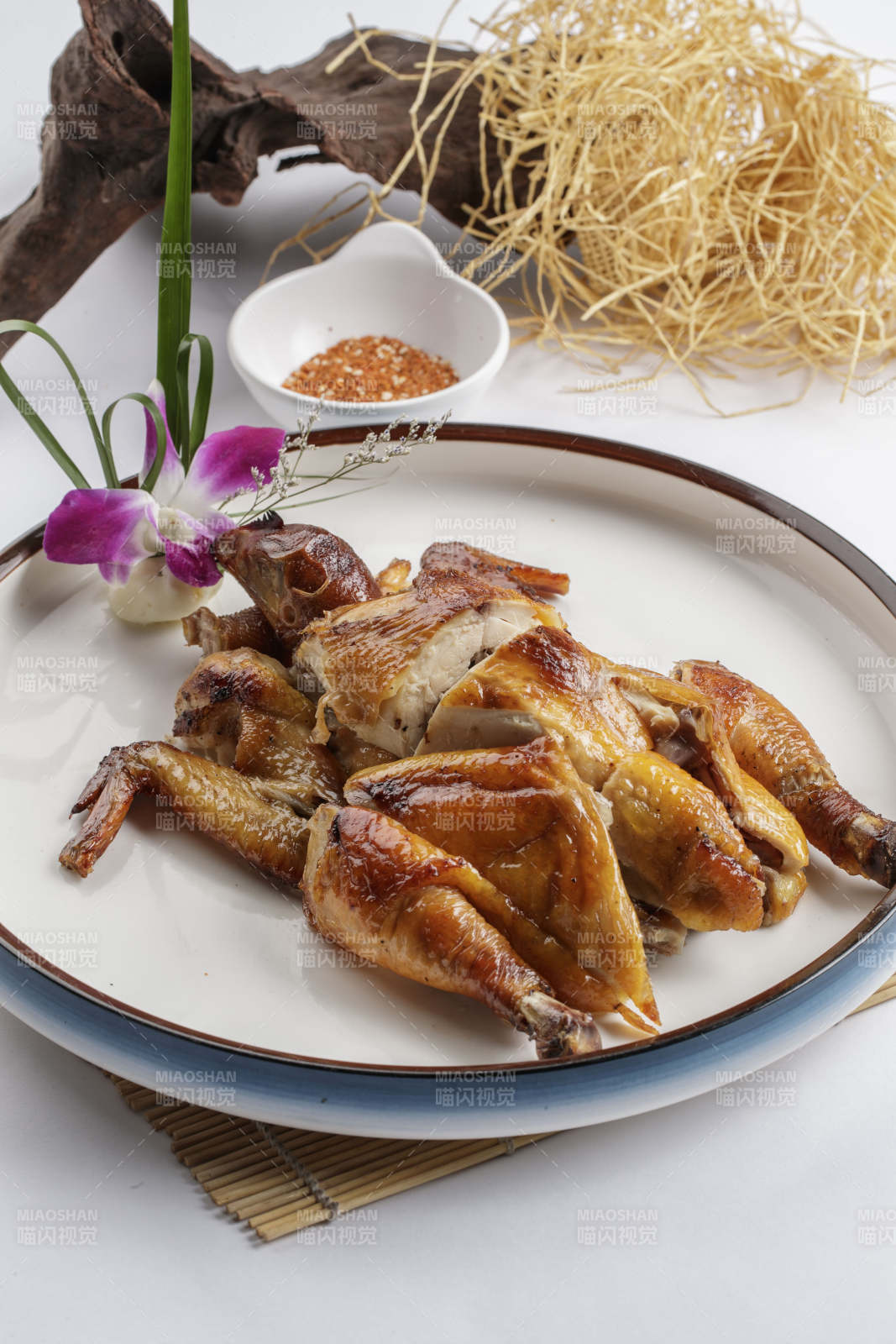 寿司帘上的圆瓷盘装的香酥脆皮鸡图片