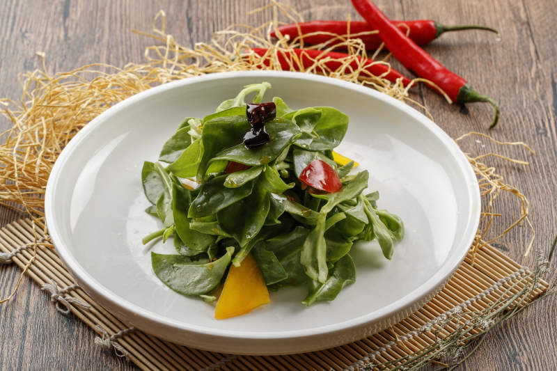 寿司帘上的圆瓷盘装的凉拌穿心莲图片