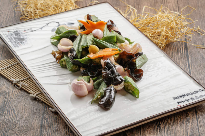 木质底纹上的长瓷盘装的木耳洋葱炒秋葵图片