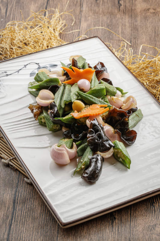 木质底纹上的长瓷盘装的木耳洋葱炒秋葵图片