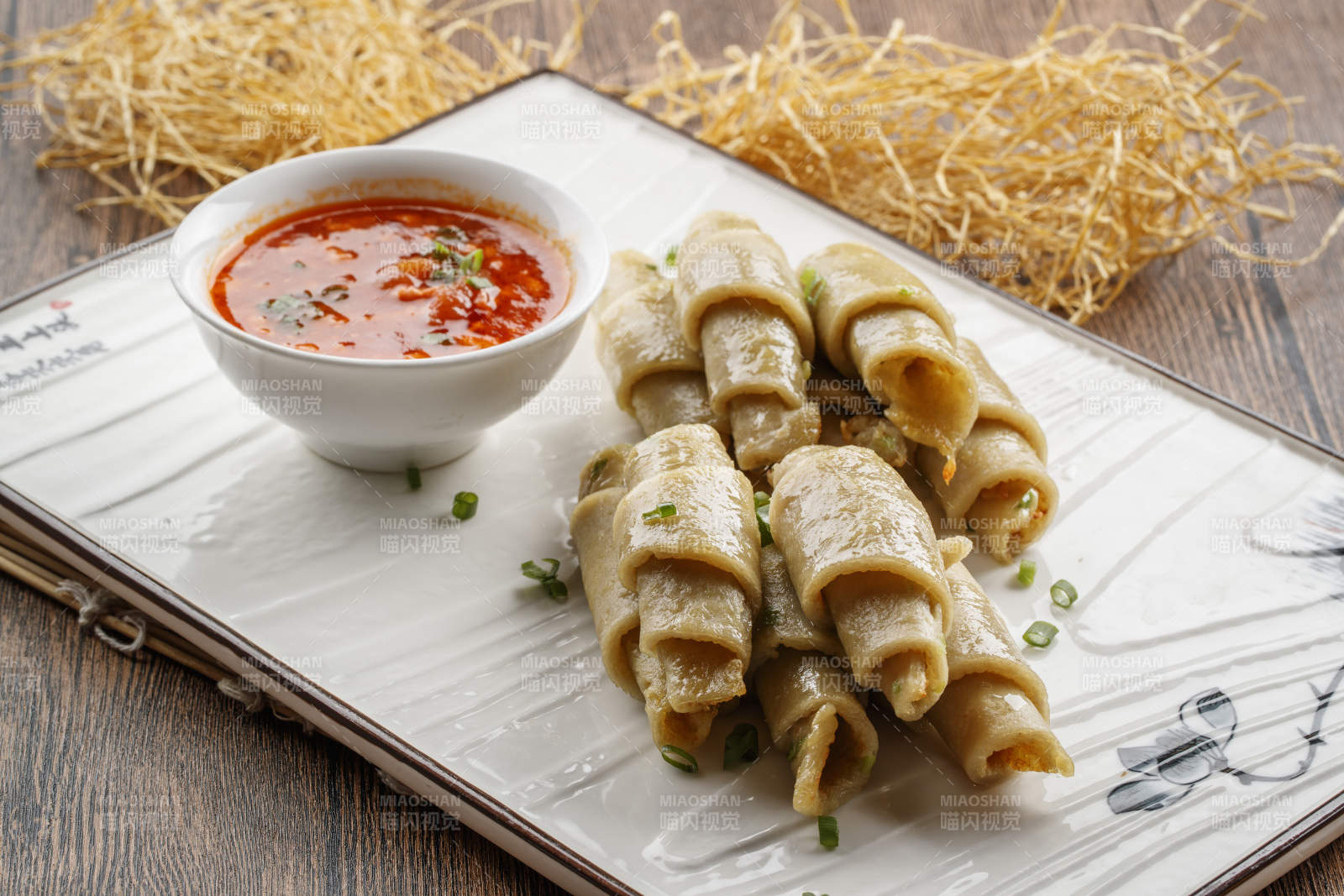 木质底纹上的长瓷盘装的蘸汁面筋卷图片