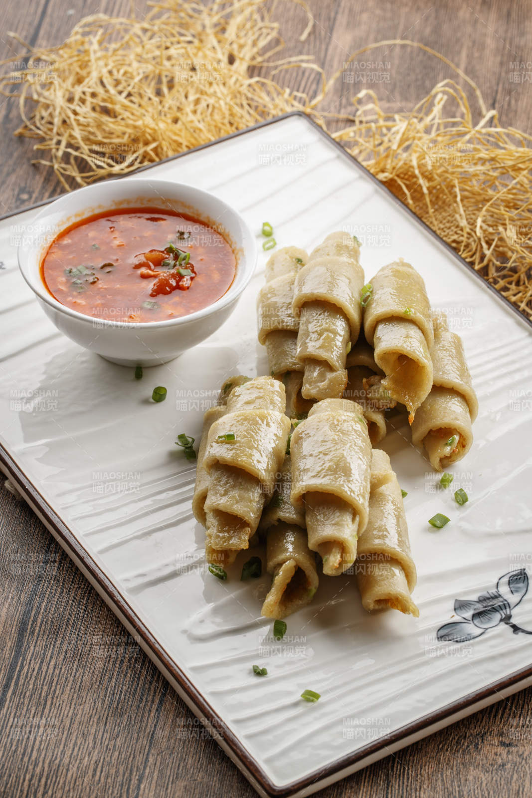 木质底纹上的长瓷盘装的蘸汁面筋卷图片