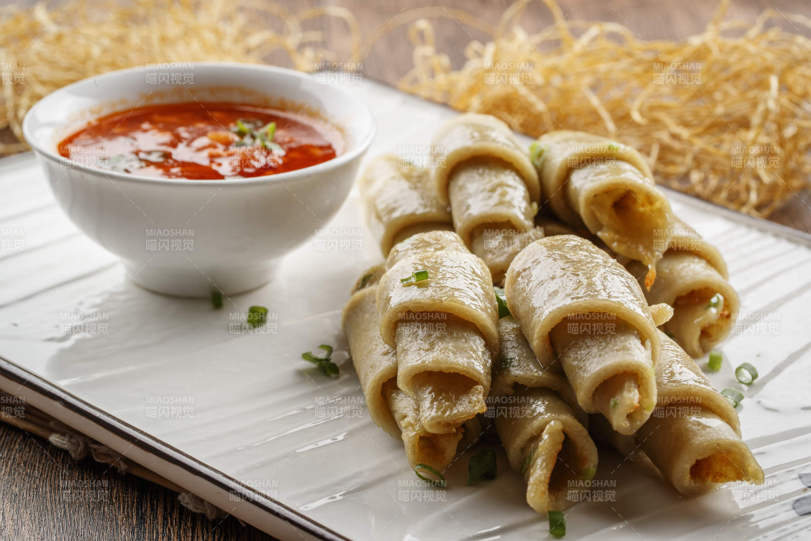 木质底纹上的长瓷盘装的蘸汁面筋卷图片