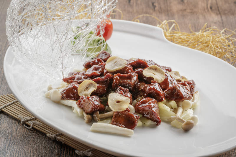 椭圆瓷盘装的蒜香海鲜菇黑椒酱牛仔粒图片