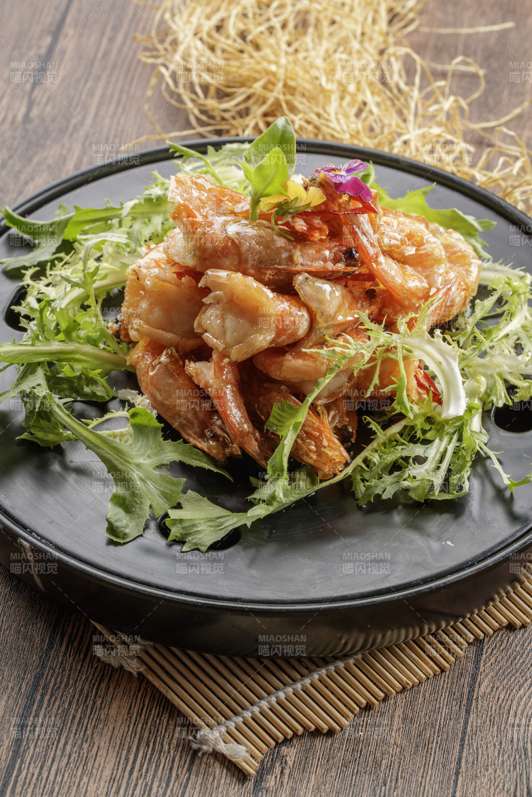 木质底纹上的黑石盘装的油炸大明虾图片