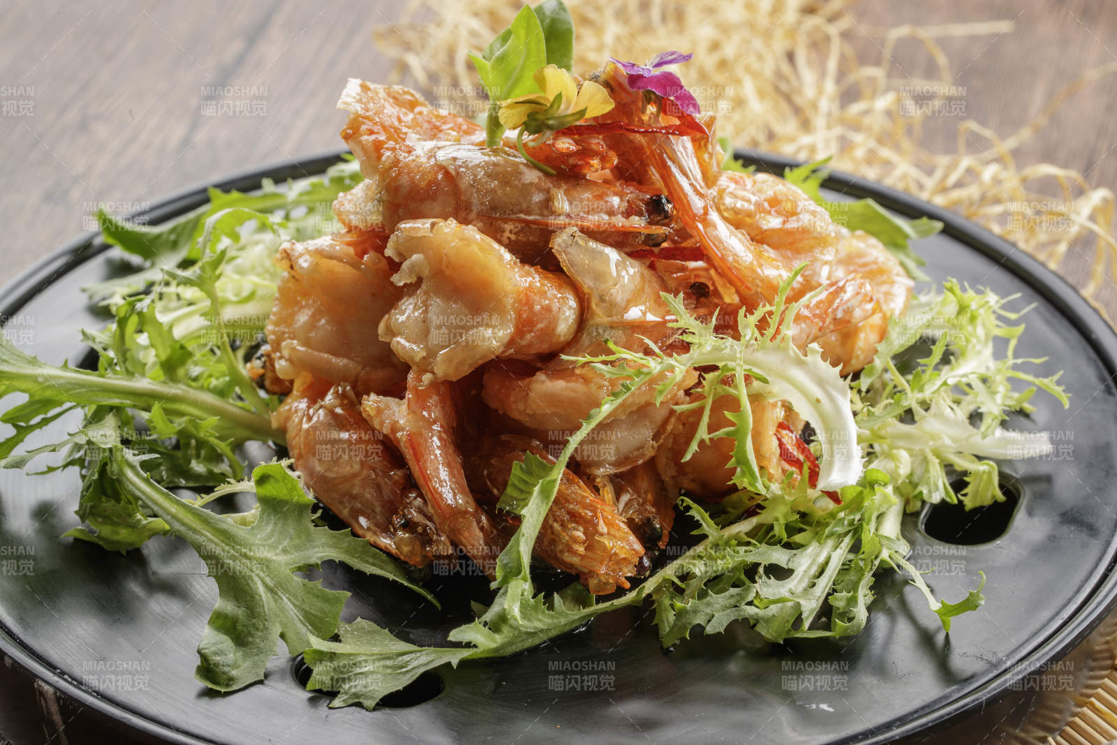 木质底纹上的黑石盘装的油炸大明虾图片