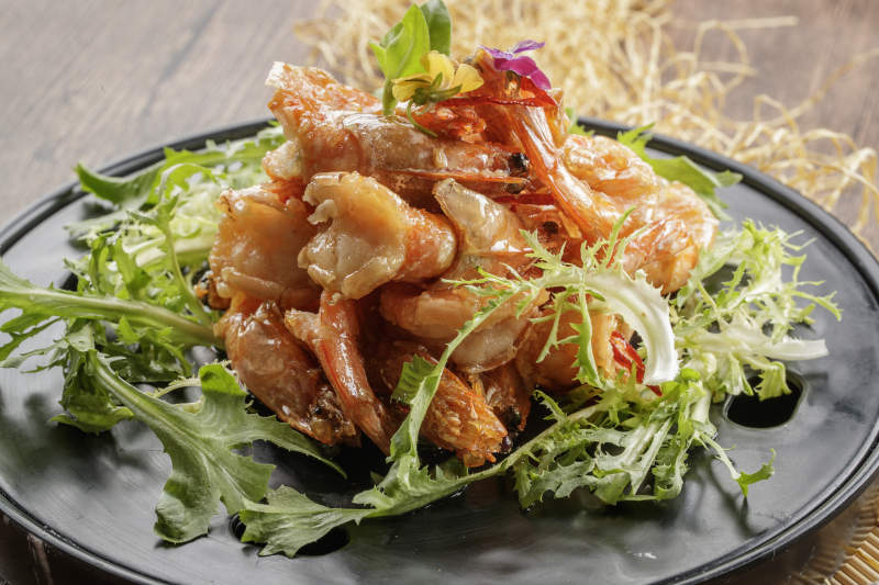 木质底纹上的黑石盘装的油炸大明虾图片