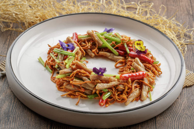 木质底纹上的圆瓷盘装的虫草花煸里脊丝图片