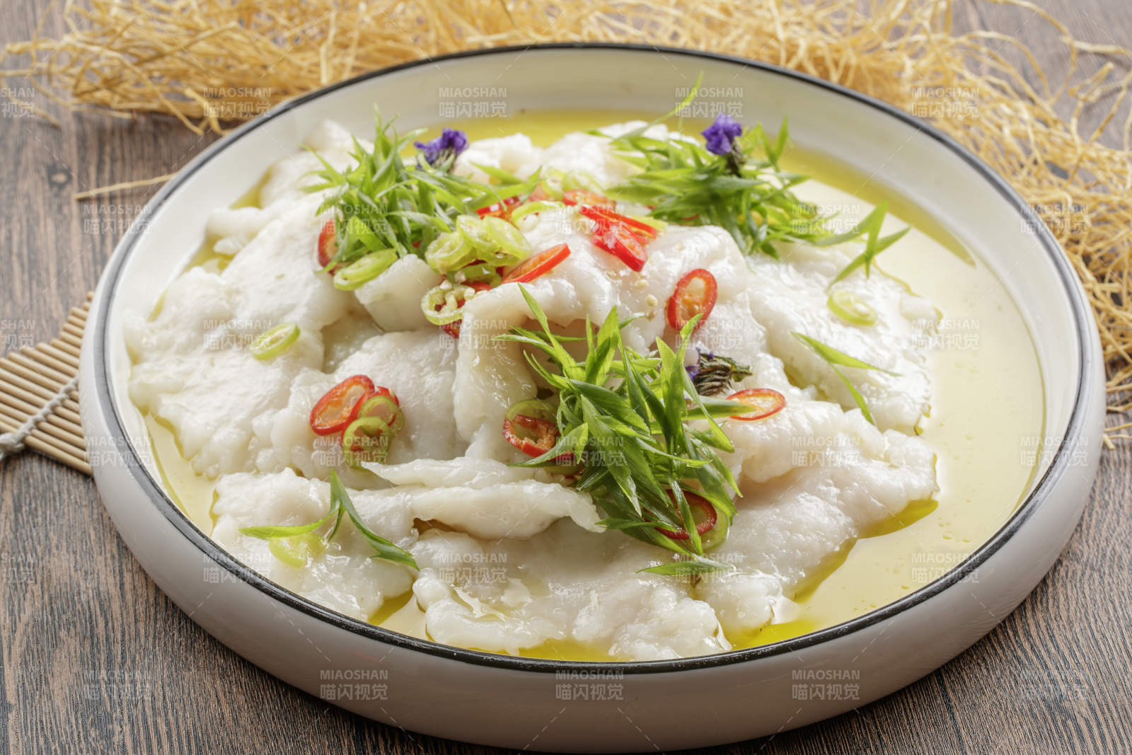 木质底纹上的圆瓷盘装的酸汤龙利鱼片图片