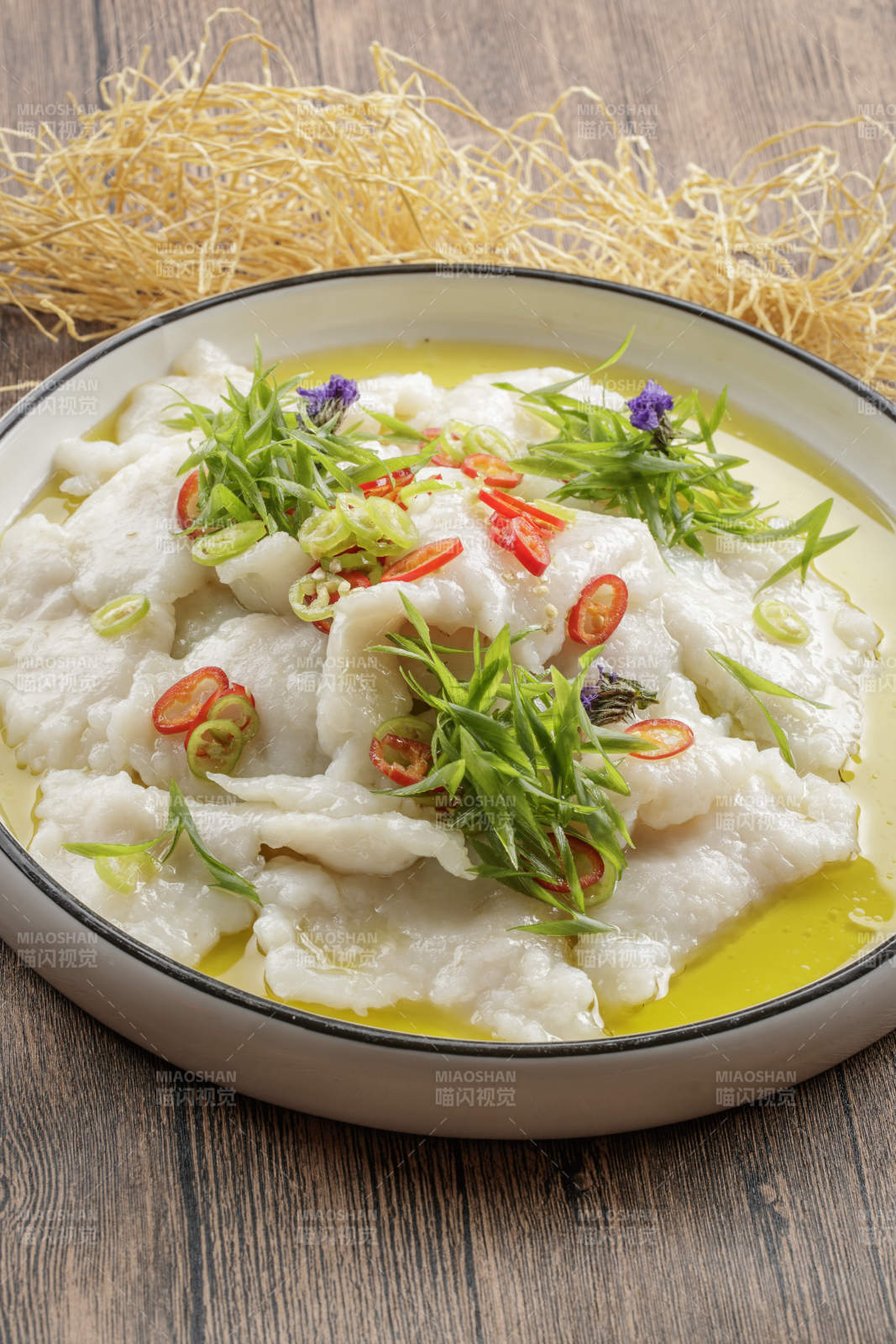 木质底纹上的圆瓷盘装的酸汤龙利鱼片图片