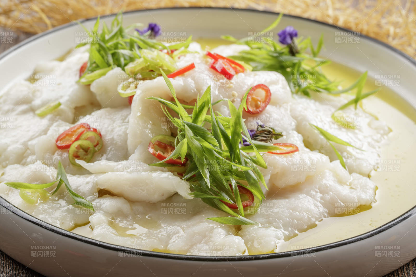 木质底纹上的圆瓷盘装的酸汤龙利鱼片图片