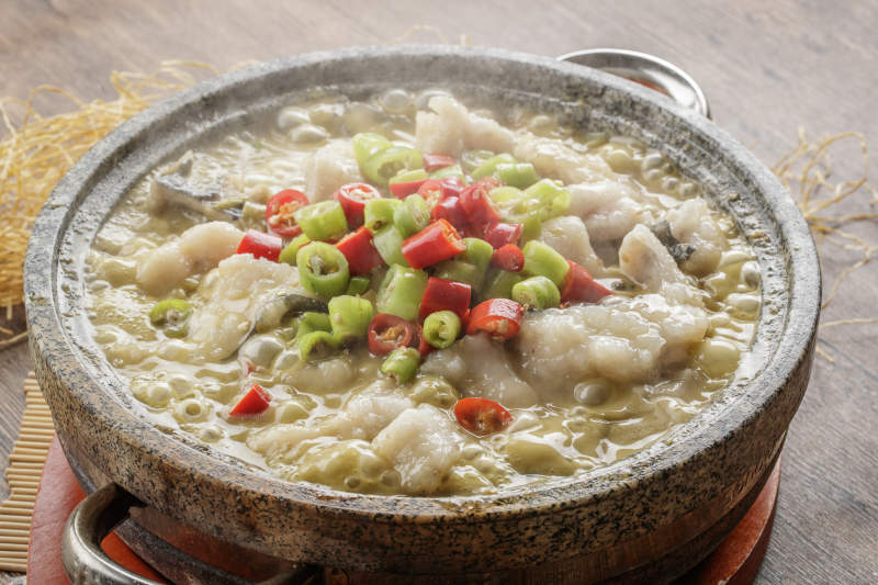 红木托盘上的石锅装的湘味沸腾鱼图片