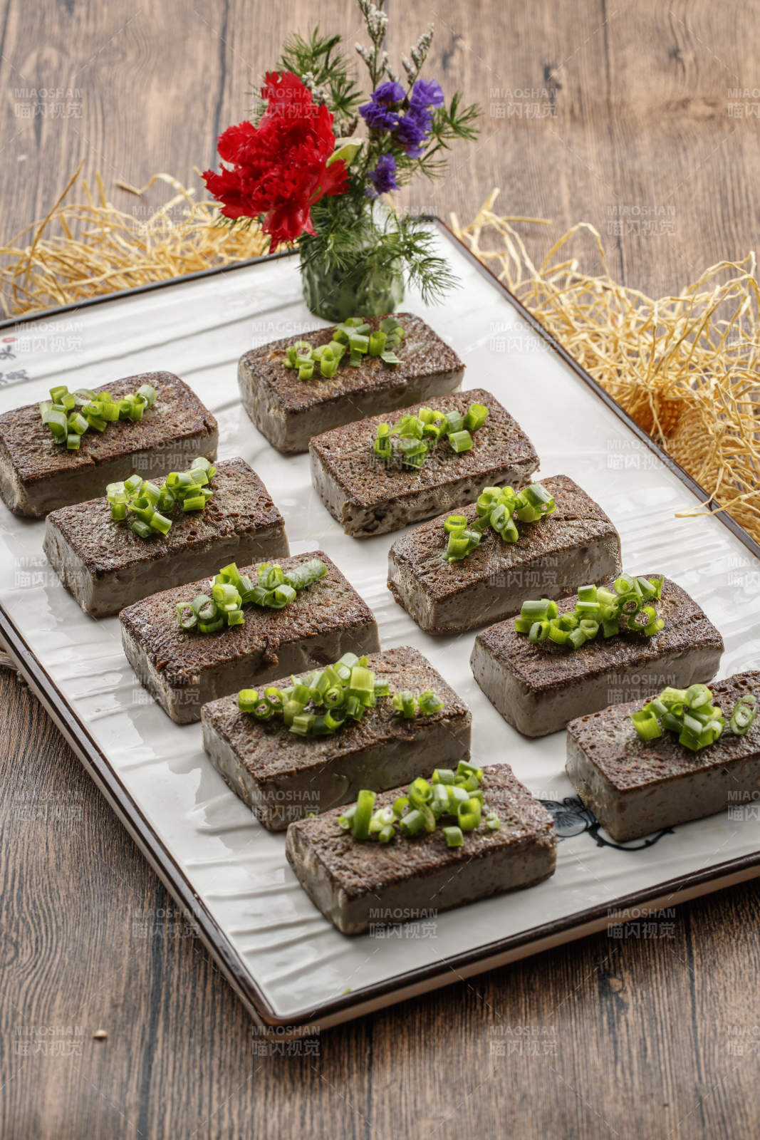 木纹底板上的长瓷盘装的香煎麻豆腐图片