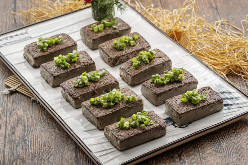 木纹底板上的长瓷盘装的香煎麻豆腐图片