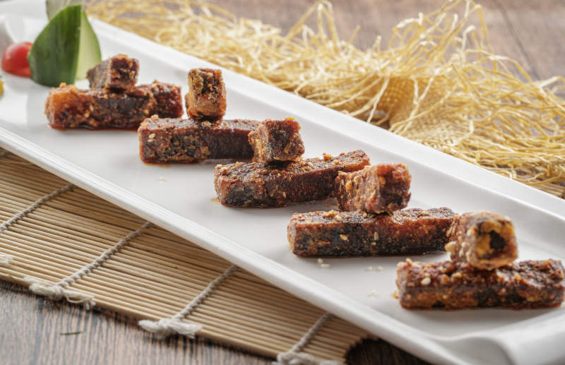 寿司帘上的长瓷盘装的麻辣猪油渣图片