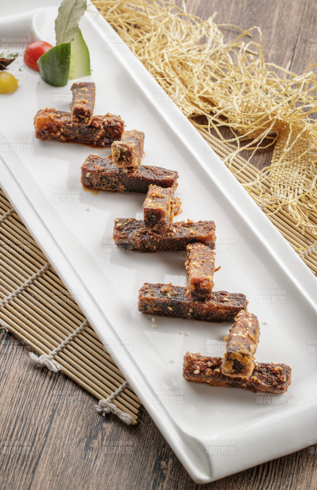 寿司帘上的长瓷盘装的麻辣猪油渣图片