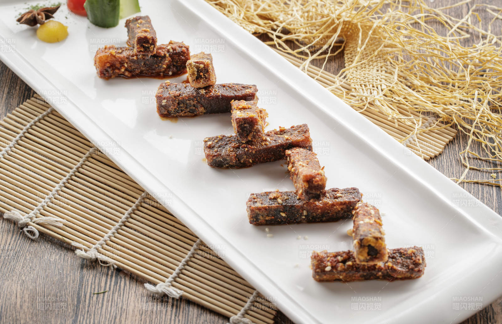 寿司帘上的长瓷盘装的麻辣猪油渣图片