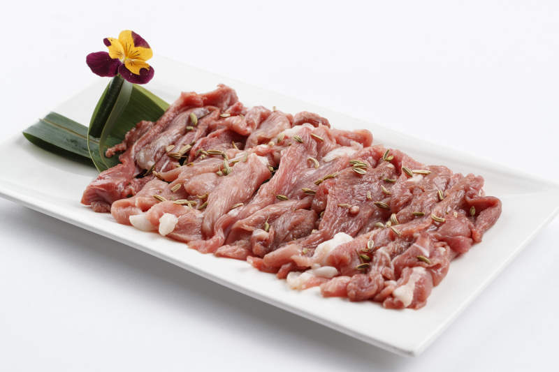 长方形白瓷盘装的鲜切羊后腿肉图片