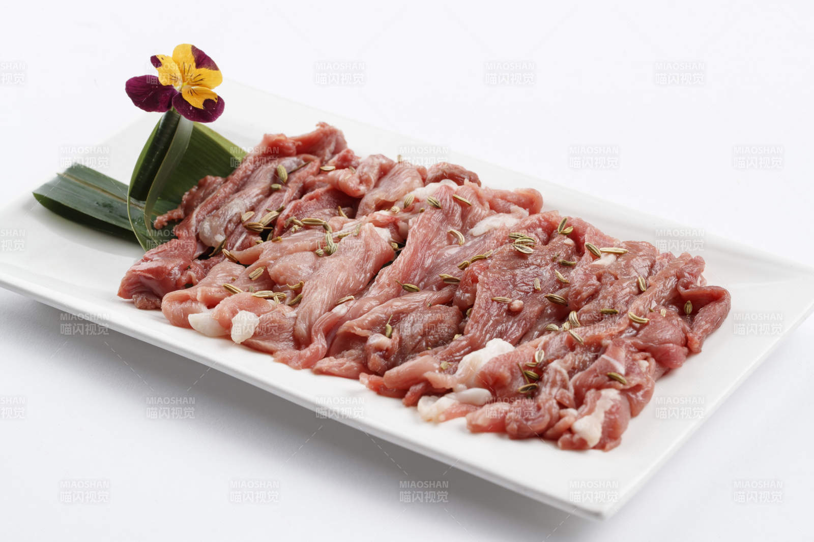 长方形白瓷盘装的鲜切羊后腿肉图片