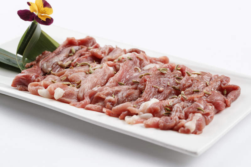 长方形白瓷盘装的鲜切羊后腿肉图片