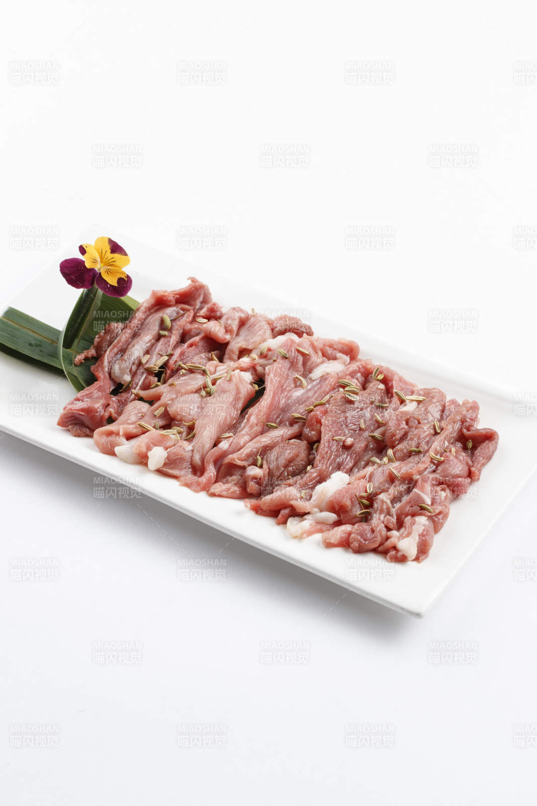 长方形白瓷盘装的鲜切羊后腿肉图片
