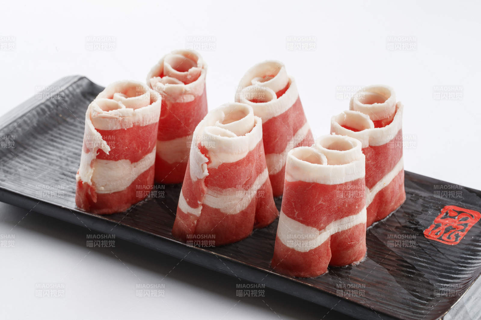 长方形黑色瓷盘装的羊五花卷图片