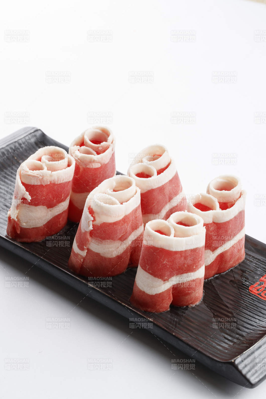 长方形黑色瓷盘装的羊五花卷图片