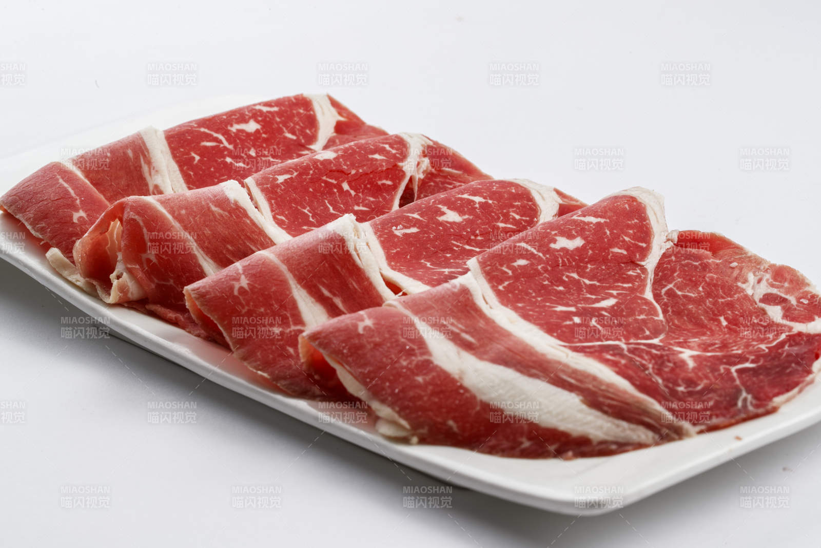 长方形白瓷盘装的牛肉片图片