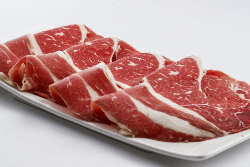 长方形白瓷盘装的牛肉片图片