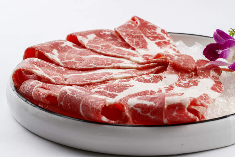 铺满碎冰的圆形瓷盘装的雪花肥牛片图片