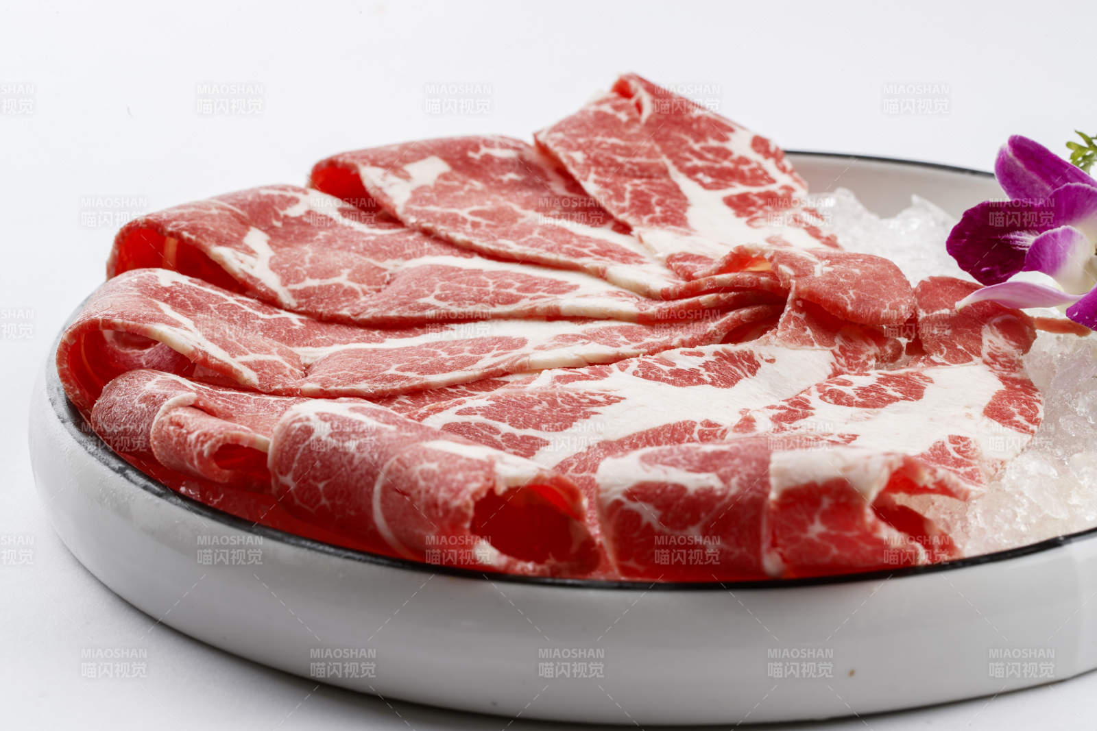 铺满碎冰的圆形瓷盘装的雪花肥牛片图片