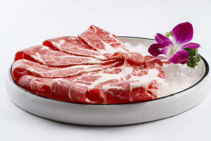 铺满碎冰的圆形瓷盘装的雪花肥牛片图片