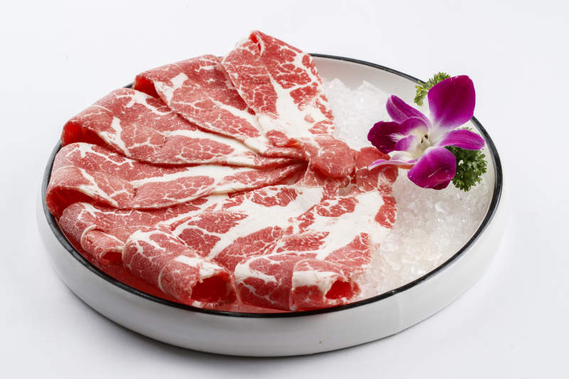 铺满碎冰的圆形瓷盘装的雪花肥牛片图片