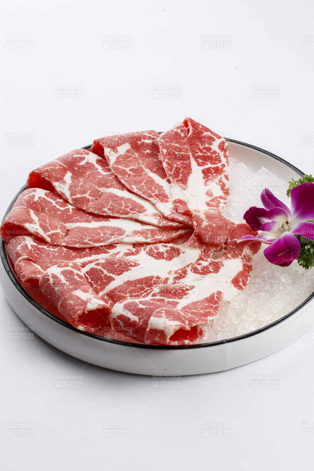 铺满碎冰的圆形瓷盘装的雪花肥牛片图片