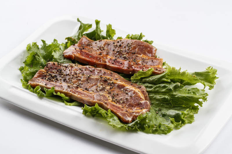 长方形白瓷盘装的黑胡椒腌制牛排肉图片