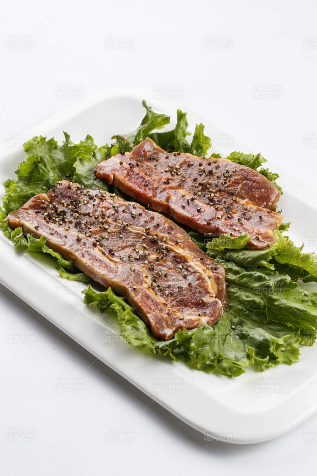 长方形白瓷盘装的黑胡椒腌制牛排肉图片